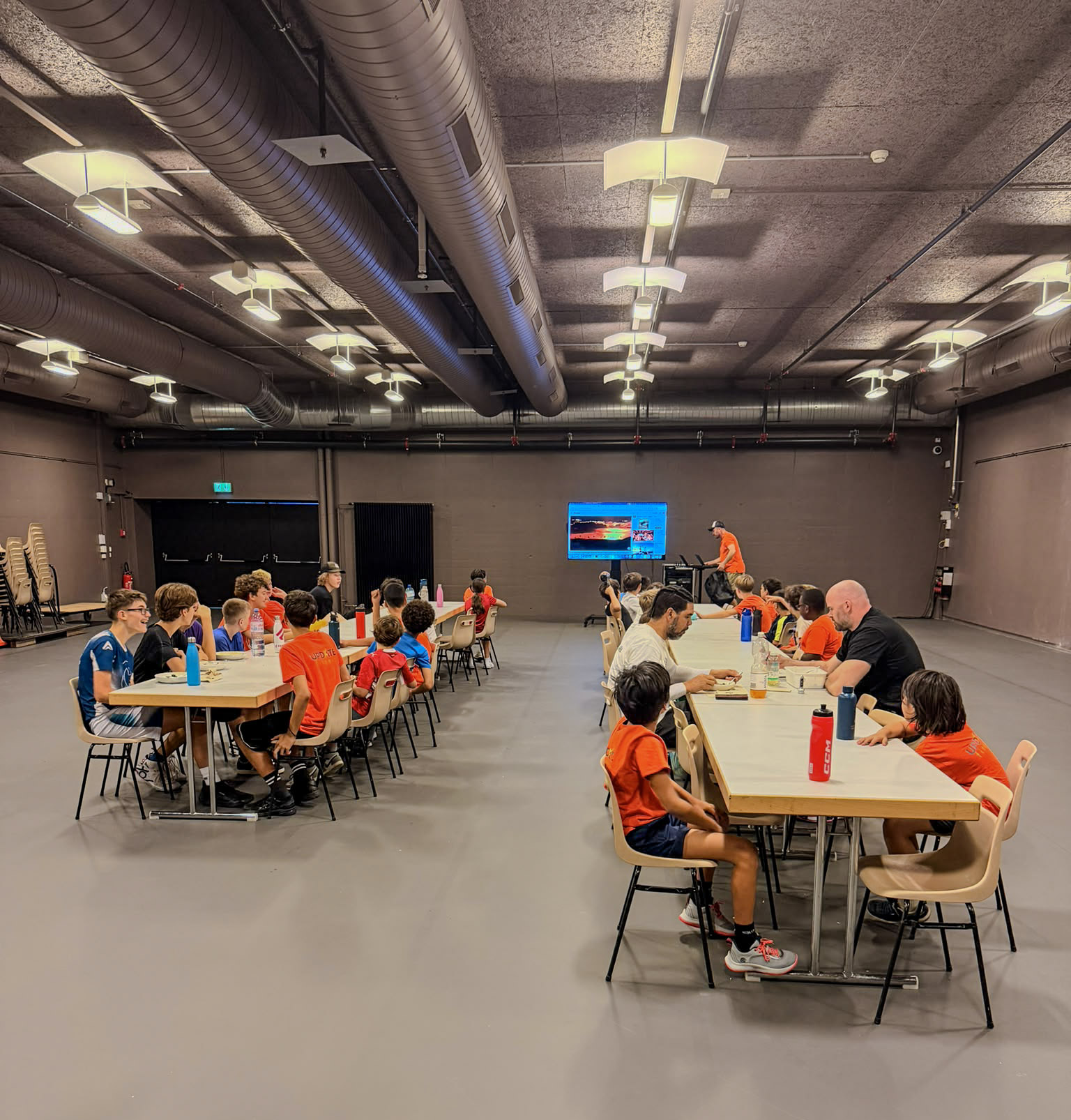 Camper und Trainer essen gemeinsam an langen Tischen