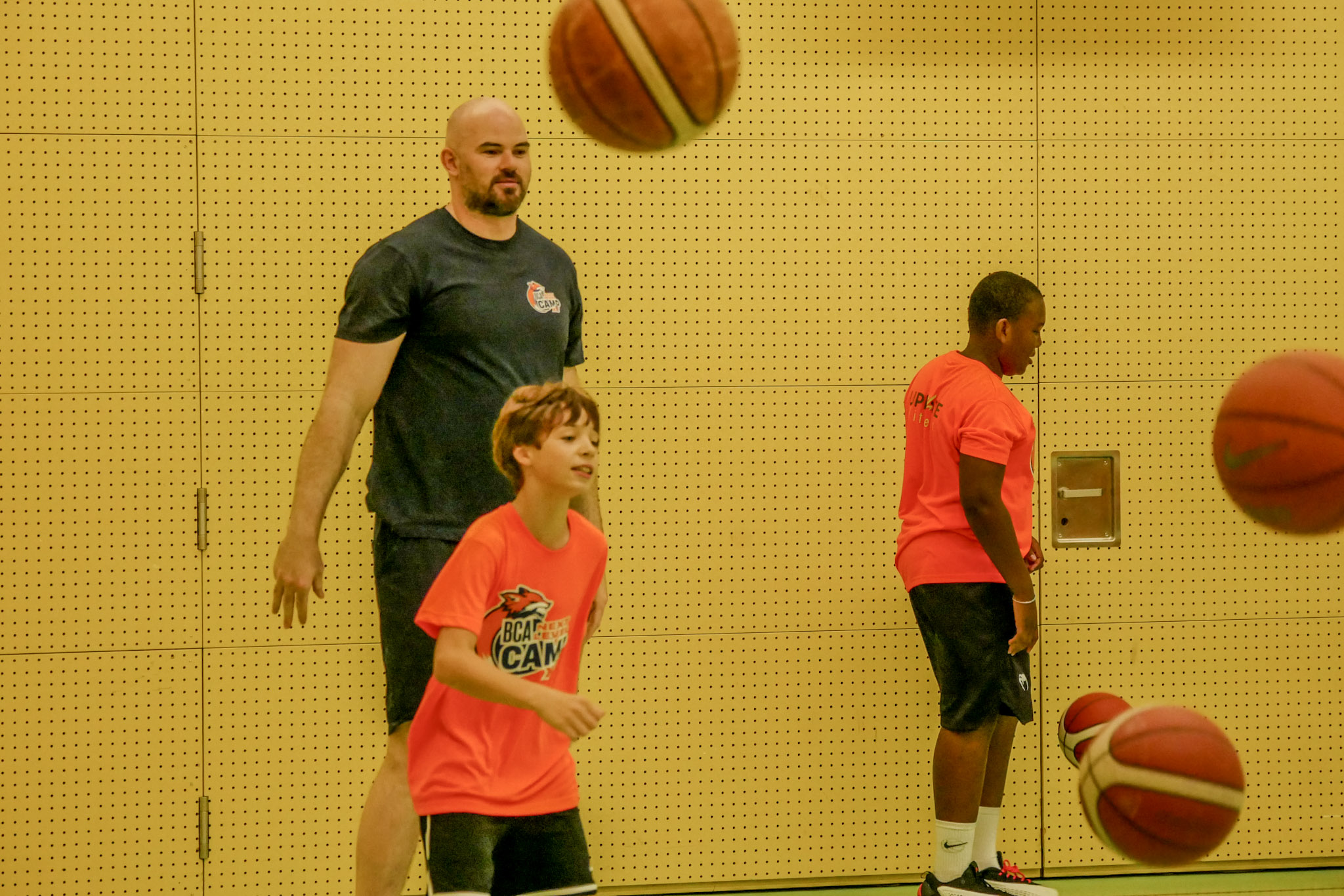 Ein Trainer begleitet einen Camper beim Dribbeltraining
